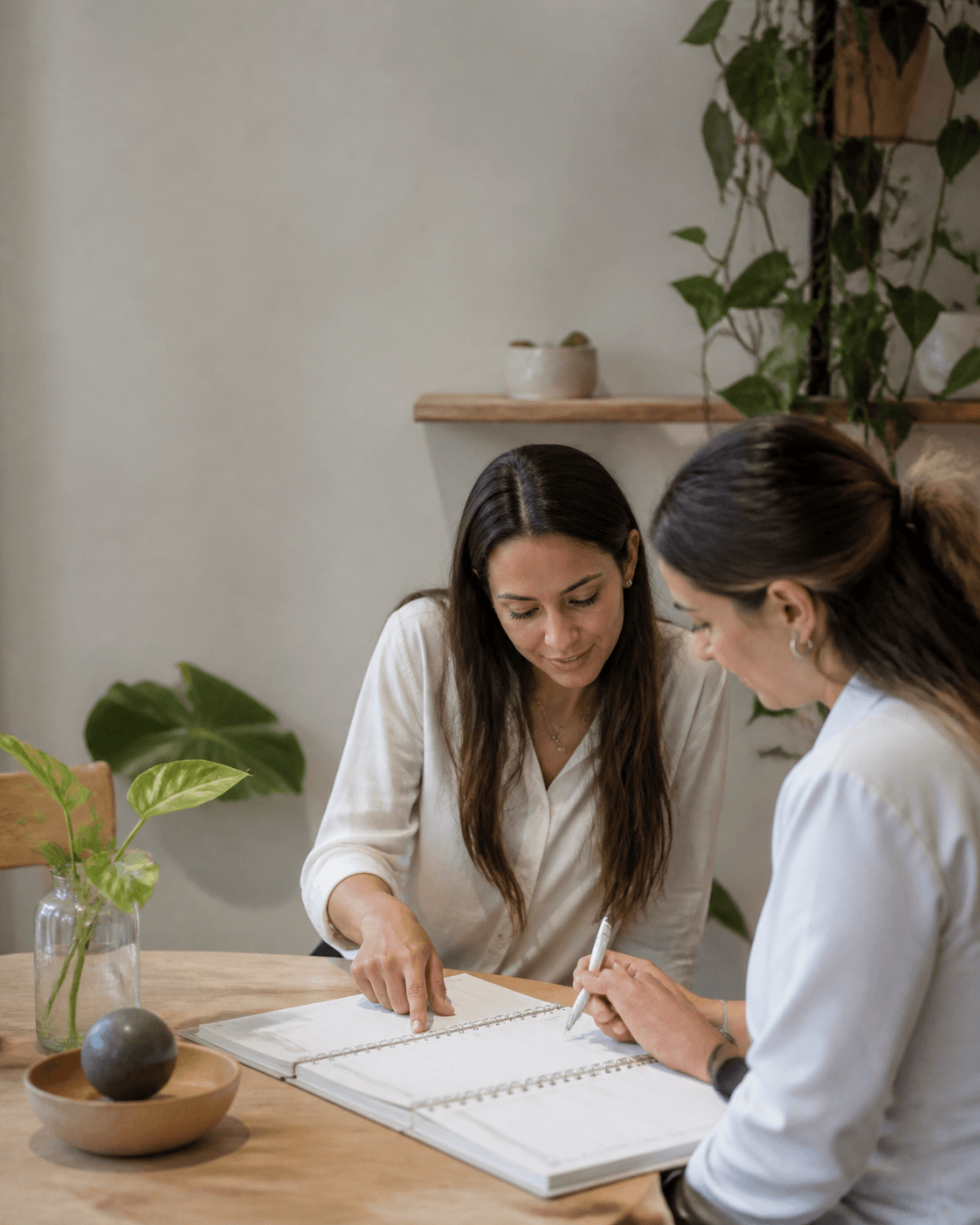 Duas profissionais colaborando sobre uma agenda em mesa de trabalho